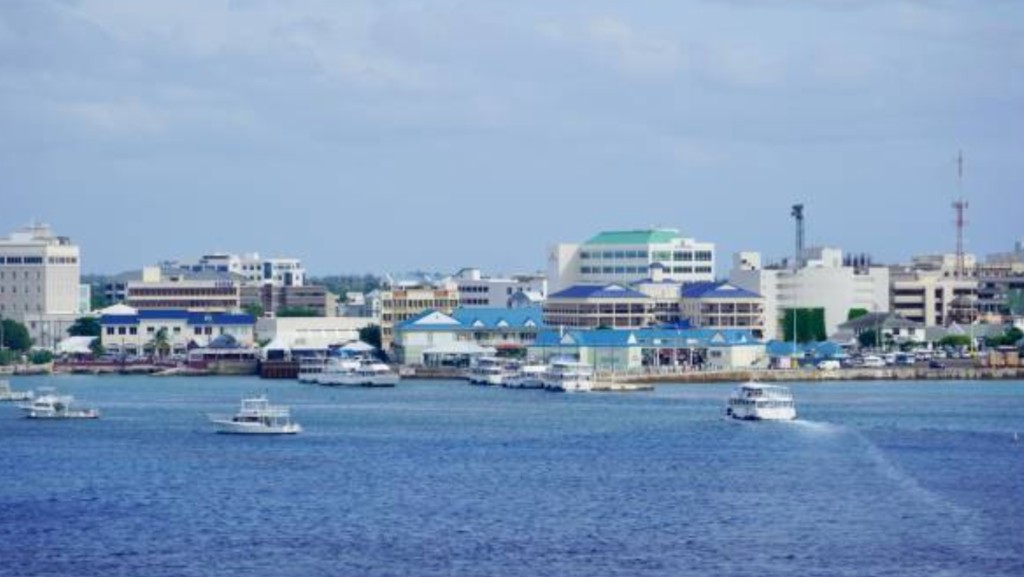 George Town Grand Cayman waterfront with cruise passenger tender boats in the harbour and colourful port buildings with blue roofs under a clear sky